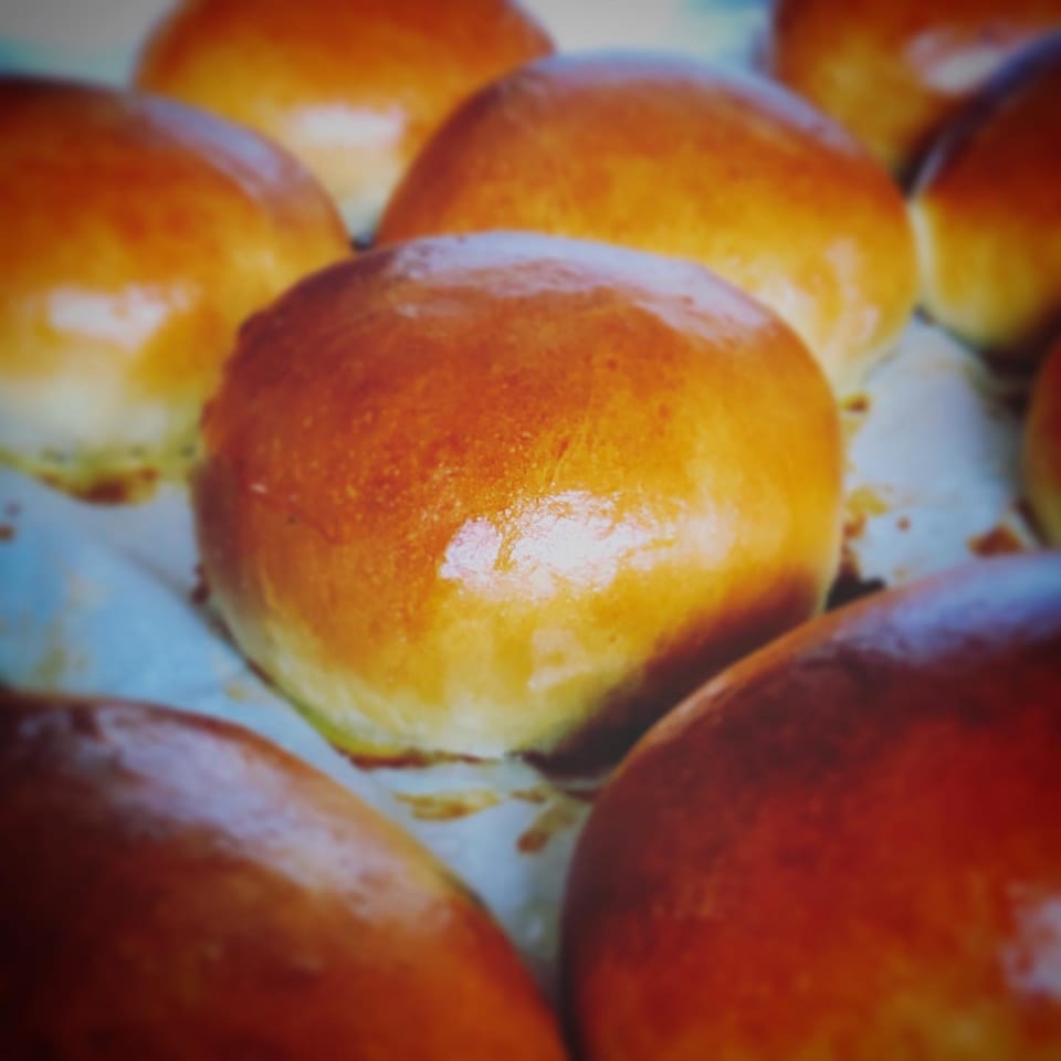 Close-up of several golden-brown, freshly baked Chinese buns with a glossy finish.